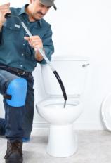 Plumber clears a toilet drain line with a snake